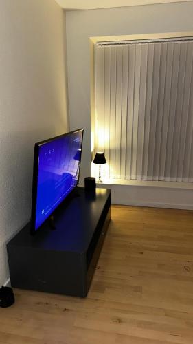 uma televisão de ecrã plano sentada numa mesa preta num quarto em Cost central flat em Aalborg