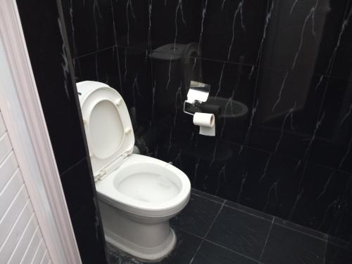 La salle de bains est pourvue de toilettes et d'un mur carrelé noir. dans l'établissement Cozy Apartment with Pool & 10 mins walk to Beach, à Mont Choisy