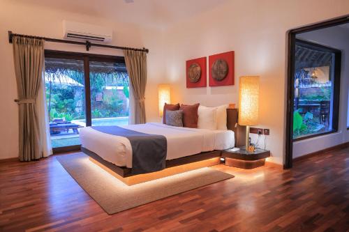 a bedroom with a bed and a large window at Marari Beach Resort Alleppey - A CGH Earth Experience in Alleppey