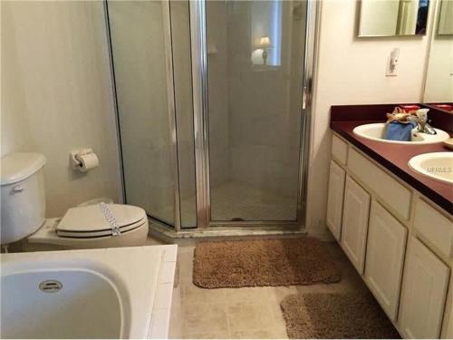 y baño con ducha, aseo y lavamanos. en Lovely 4Bd Gm Spa Pool Hm Glenbrook-1616MSD, en Orlando