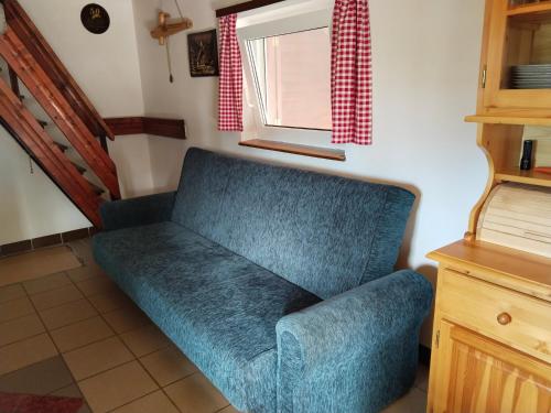 a blue couch in a room with a window at Wooden Treasure in Jesenice