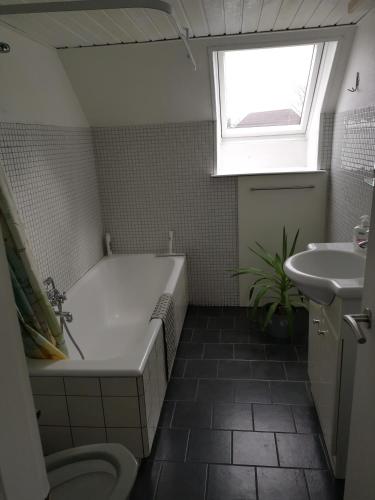 a bathroom with a tub and a sink and a window at Skolevænget 35 in Skjern