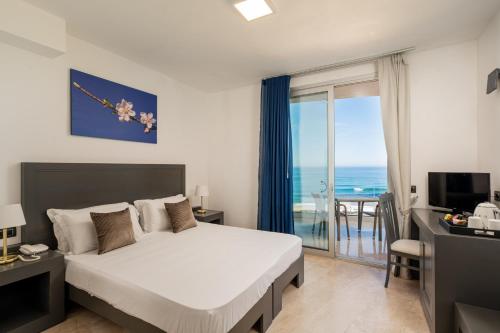 a bedroom with a bed and a view of the ocean at Bellevue Sardinia Resort, Affiliated by Meliá in Valledoria