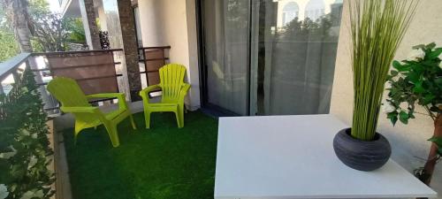 - deux chaises vertes et une table sur un balcon dans l'établissement Les Jardins de Louis, à Cannes