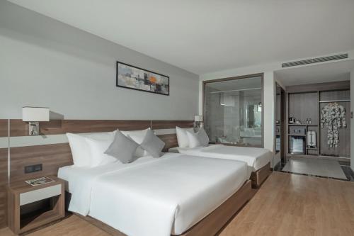 a bedroom with two large white beds and a window at PANAMA Nha Trang Hotel in Nha Trang