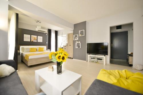 een woonkamer met een bed en een vaas met bloemen bij Reina Apartments Skopje in Skopje