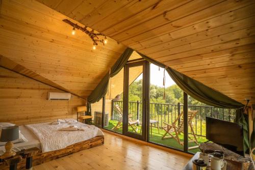 a bedroom with a bed and a large window at ციბენა • Tsibena in Ambrolauri