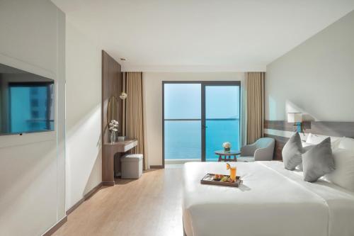 a bedroom with a white bed and a view of the ocean at PANAMA Nha Trang Hotel in Nha Trang