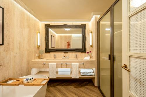 a bathroom with a tub and a sink and a mirror at Only YOU Hotel Sevilla in Seville