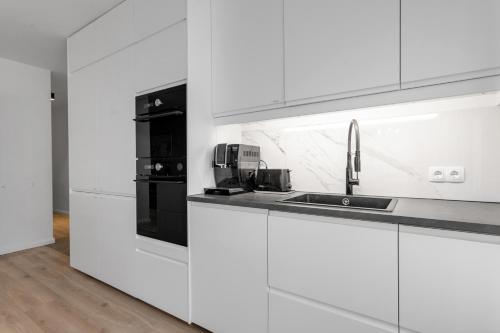 a white kitchen with white cabinets and a sink at Stylish 3BR Apartment in Reykjavík