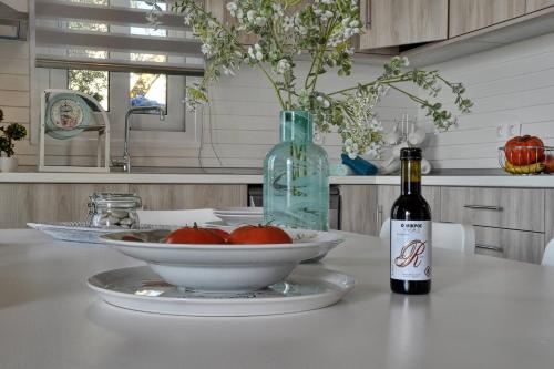 a table with a bowl of tomatoes and a bottle of wine at Lefkimmiatis Villas Corfu in Afionas
