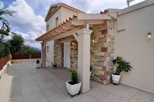 a house with a patio with potted plants on it at Lefkimmiatis Villas Corfu in Afionas