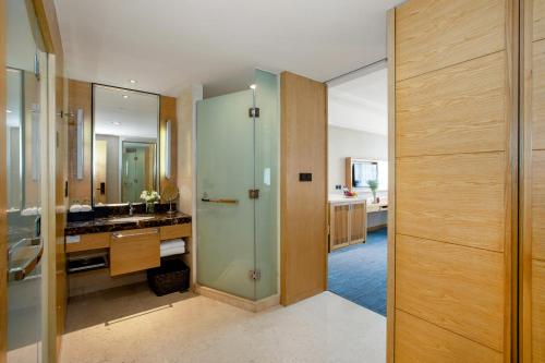 a bathroom with a glass shower and a sink at Yiho Hotel Xiamen Huli in Xiamen