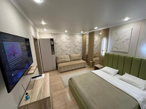 um quarto com uma cama grande e uma televisão de ecrã plano em Уютная, новая квартира в центре города em Qostanay