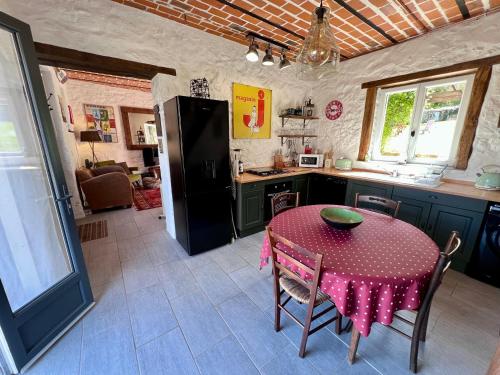 Il comprend une cuisine équipée d'une table et d'un réfrigérateur noir. dans l'établissement Gite Marie Ange, à Marsac