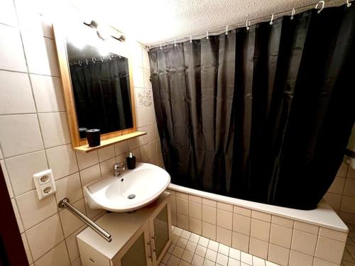 a bathroom with a sink and a black shower curtain at Genau so - Allgäu! Sau Gemütlich in Maierhöfen