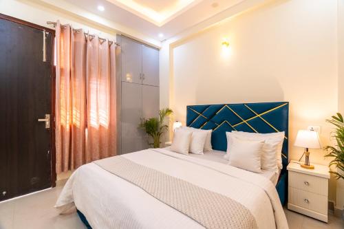a bedroom with a large bed with a blue headboard at Homlee-Vasundhara 3BHK Flat- kitchen-Parking-Lift in Ghaziabad