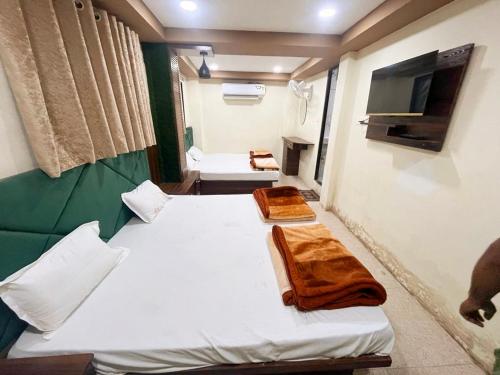Habitación pequeña con 2 camas y TV. en Green leaf Hotel en Ujjain