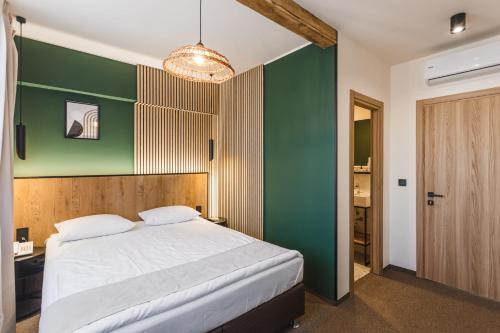 a bedroom with a bed and a green wall at Stokker Hotel in Oradea