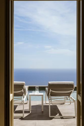two chairs and a table on a balcony with the ocean at Almarossa Luxury Villas in Vourvoulos