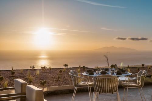 uma mesa e cadeiras num pátio com vista para o oceano em Almarossa Luxury Villas em Vourvoúlos