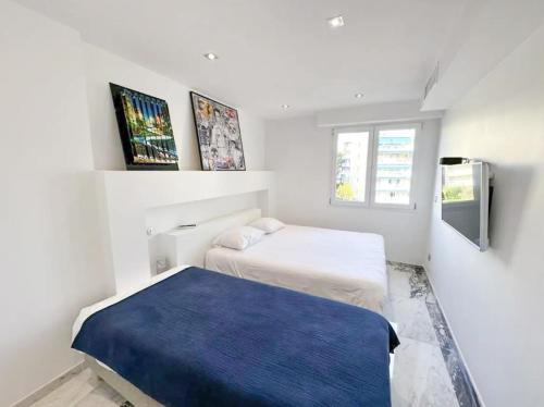 - une chambre blanche avec 2 lits et une couverture bleue dans l'établissement Modern 3 bedroom flat with balcony, à Cannes