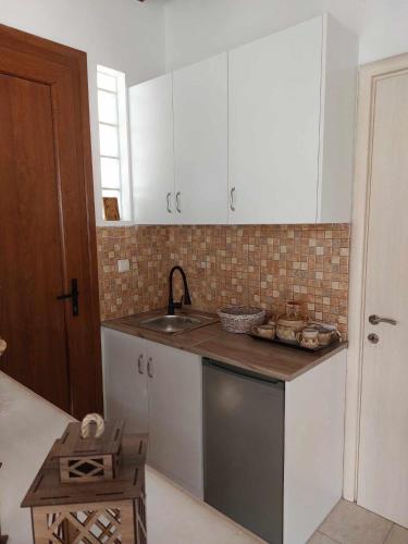 a kitchen with white cabinets and a sink at Boheme studio Artemis in Áyios Spirídhon