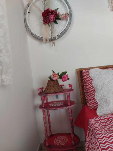 a red shelf with a wreath on a wall next to a bed at Boheme studio Artemis in Áyios Spirídhon
