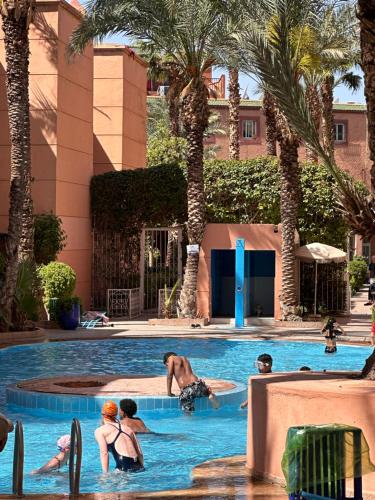 un groupe de personnes dans une piscine bordée de palmiers dans l'établissement Riad Hicham, à Marrakech