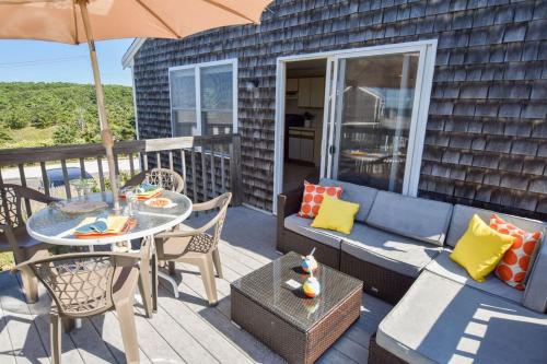 a patio with a couch and a table and an umbrella at Beautiful Views of Cape Cod Bay in Truro