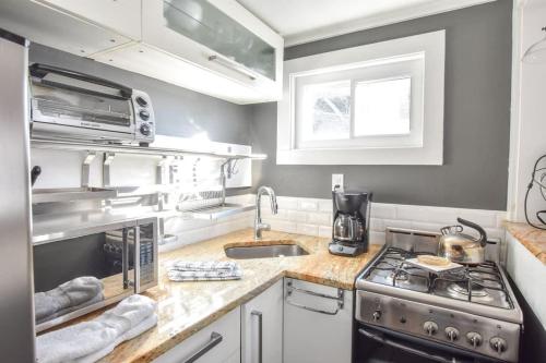 Una pequeña cocina con estufa y fregadero. en Gas Fireplace Front Patio & Parking Spot, en Provincetown