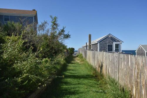 a fence next to a house and a building at Beautiful Views of Cape Cod Bay in Truro