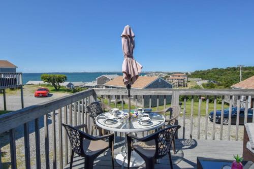 a table with chairs and an umbrella on a balcony at 12216 - Beautiful Views of Cape Cod Bay Access to Private Beach Easy Access to P-Town in Truro