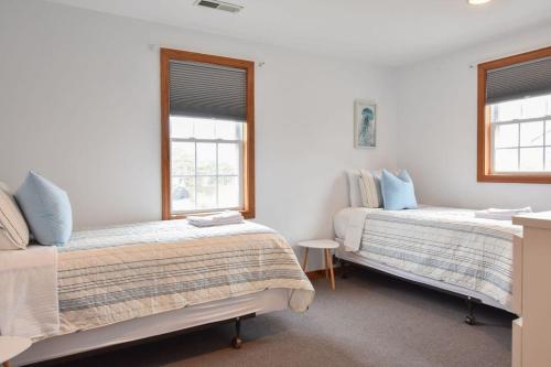 ein Schlafzimmer mit zwei Betten und zwei Fenstern in der Unterkunft 12217 - Beautiful Views of Cape Cod Bay Access to Private Beach Easy Access to P-Town in Truro