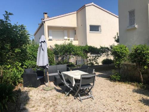 una mesa, sillas y una sombrilla frente a una casa en Petit appartement tranquille avec jardin - Hyeres Centre Ville en Hyères
