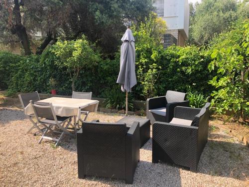 a patio with a table and chairs and an umbrella at Petit appartement tranquille avec jardin - Hyeres Centre Ville in Hyères