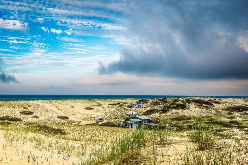 a house in the middle of a sandy beach at 12215 - Beautiful Views of Cape Cod Bay Access to Private Beach Easy Access to P-Town in Truro
