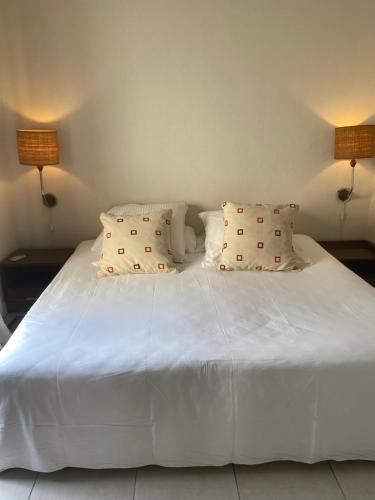 - un lit blanc avec 2 oreillers et 2 lampes dans l'établissement Le Colonial Cocoon Apartement 2, à La Gaulette
