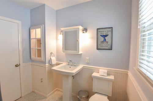 a bathroom with a sink and a toilet and a mirror at Classic Cape Great Location Dog Welcome in Wellfleet