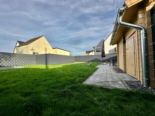 einen Rasenplatz neben einem Gebäude mit einem Zaun in der Unterkunft Chalet Lasserg in Münstermaifeld