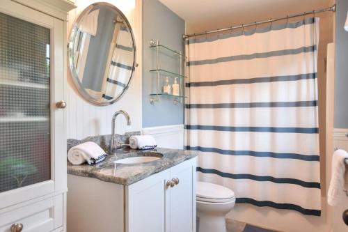 a bathroom with a sink and a toilet and a mirror at Private Patio Walk to Commercial St in Provincetown