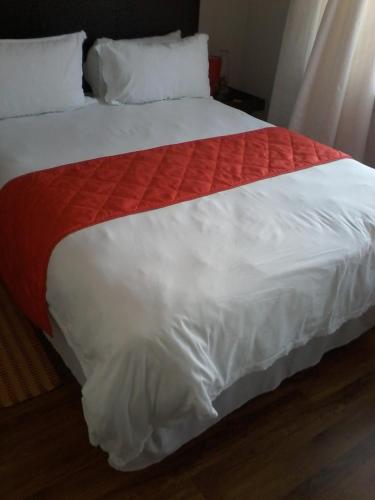 uma cama com um cobertor vermelho e branco em Palm Springs B and B and Self Catering em Butterworth