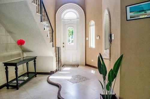 a hallway with a staircase with a red flower on a table at Ocean Pearl Villa in Saint James