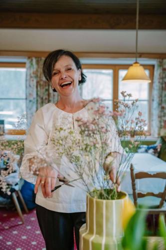a woman is standing next to a yellow cake at Hotel-Pension Faneskla in Silbertal