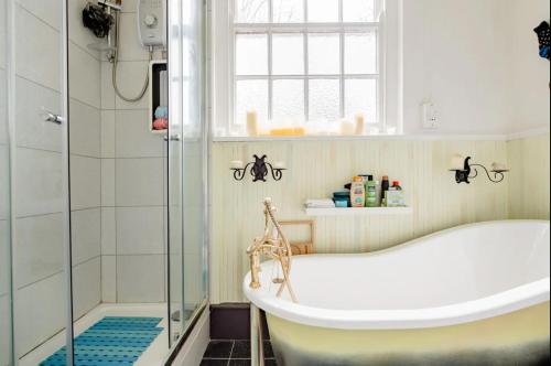 a bathroom with a tub and a glass shower at Georgian house in Billericay - quirky & homely in Billericay