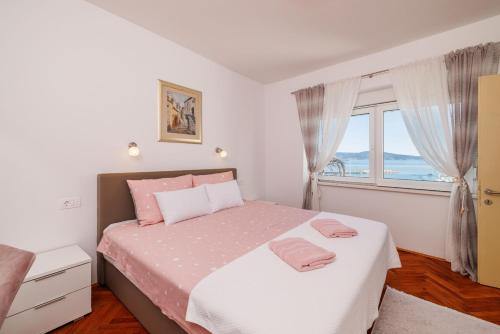 um quarto com uma cama com lençóis cor-de-rosa e uma janela em House Sea La Vie em Novi Vinodolski