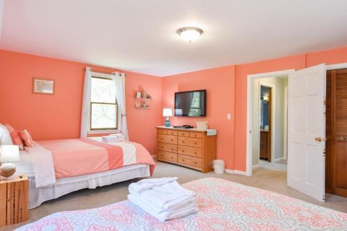 a bedroom with orange walls with two beds and a tv at 14443 - Expansive Home Abutting Rail Trail Near First Encounter and Hatch Beaches in Eastham