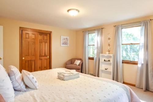 a bedroom with a bed and a chair and windows at 14443 - Expansive Home Abutting Rail Trail Near First Encounter and Hatch Beaches in Eastham