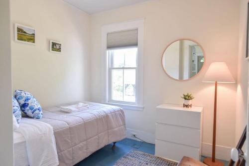 a white bedroom with a bed and a mirror at Private Downtown Wellfleet Location in Wellfleet