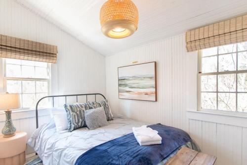 a bedroom with a bed and two windows at Seaside Retreat w Private Beach Landing in Eastham
